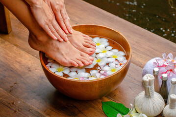 Spa Foot Soak, Relaxing foot spa treatment with herbal compresses, oils, and frangipani flowers in...