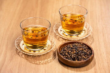 木のテーブルに並べた麦茶のグラスと焙煎大麦の粒