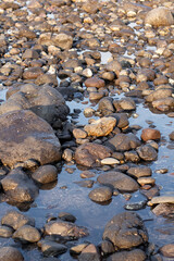 a collection of small and large stones on a beautiful beach on a sunny and cool afternoon