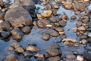 a collection of small and large stones on a beautiful beach on a sunny and cool afternoon