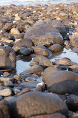 a collection of small and large stones on a beautiful beach on a sunny and cool afternoon
