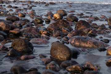 a collection of small and large stones on a beautiful beach on a sunny and cool afternoon