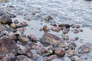a collection of small and large stones on a beautiful beach on a sunny and cool afternoon