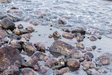 a collection of small and large stones on a beautiful beach on a sunny and cool afternoon