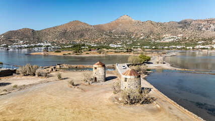 panoramic drone view of ancient mills and canal with bridge near crete island
