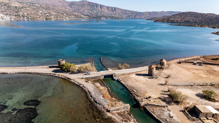 panoramic drone view of ancient mills and canal with bridge near crete island