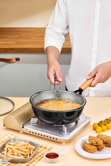 Delicious Fried Food Preparation with Stainless Steel Mesh Strainer and Modern Kitchen Stove, Chef cooking chicken nuggets in a frying pan on a kitchen