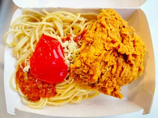 Spaghetti and fried chicken with spicy sauce on a plate.