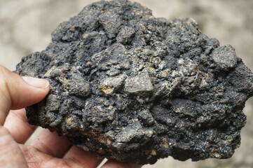 young man holding asphalt stone on damaged road