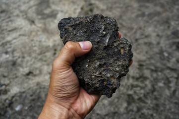 young man holding asphalt stone on damaged road
