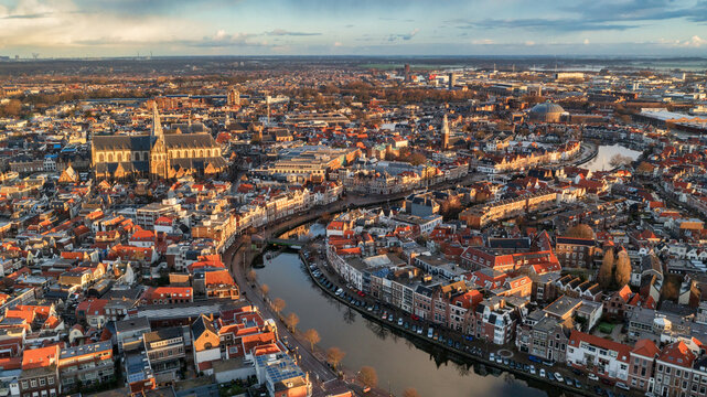 Aerial view of the Grote Markt and St. Bavo Church, a tapestry of terracotta roofs intersected by canals under a serene sky, Haarlem, North Holland, Netherlands.