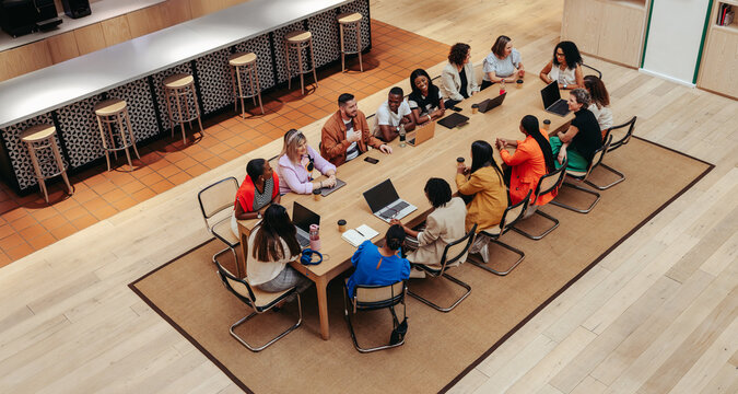 Overhead shot of diverse business meeting around a large table in modern office setting