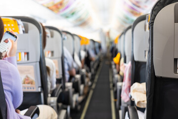 Inside commercial airplane, passengers sit calmly in economy class. Selective focus of the aisle, with blurred seats creating depth. It shows air travel, aviation lifestyle, or transportation scenes.