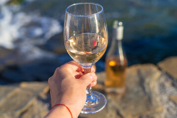 Wine in hands of woman against sea background. Selective focus.