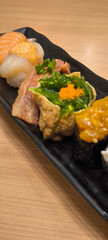 Delicious sushi platter with salmon. tuna. and roe on black plate in ambient lighting.