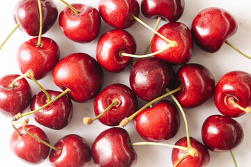 Fresh ripe cherries background. Red fruits with stems on white marble table. Sweet summer snack. Organic harvest. Natural dessert full of flavor. Healthy juicy berries for seasonal kitchen decor.