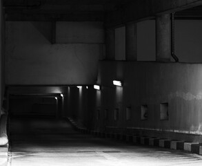 Black and white photograph of the entrance to an underground garage lit by wall sconces.