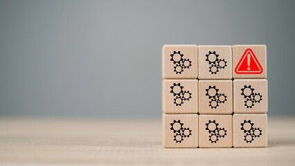 Wooden blocks with gear icons and a red warning symbol highlight a system automation process issue. Concept for error detection, operation failure, and maintenance alert.