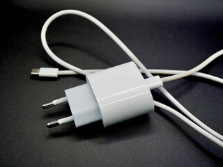 A modern white phone charger with a USB-C cable is displayed on a dark background. The clean and minimalistic design highlights the simplicity and functionality of this everyday tech accessory