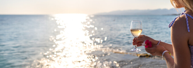 Wine in hands of woman against sea background. Selective focus.
