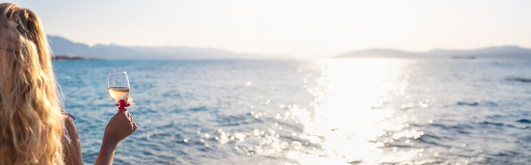 Wine in hands of woman against sea background. Selective focus.