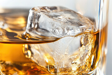 Large, clear ice cube slowly melts and swirls within a glass of rich, golden amber liquid, creating a refreshingly cool and inviting beverage.