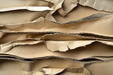 Ripped brown corrugated cardboard reveals a rough texture and layered patterns, creating an abstract background with corrugated details.