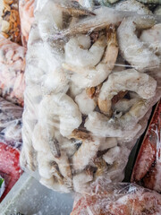 Raw frozen shrimp in a transparent plastic bag for vacuum packaging. Selective focus