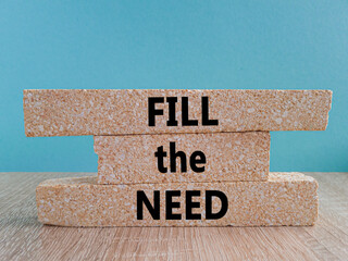 Fill the need symbol. Concept words Fill the need on brick blocks on a beautiful wooden table blue...
