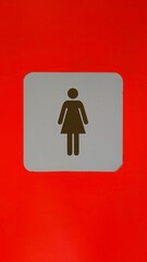 Malaga, Spain - July 25, 2025: Female restroom sign on vibrant red background indicating women's facilities in public spaces for easy identification