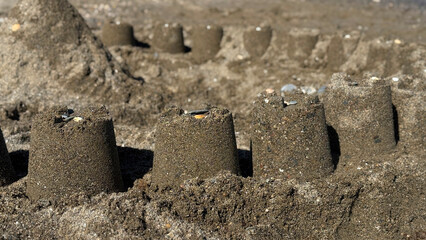 Sandcastles built on a beach, showcasing intricate designs and textures, surrounded by fine grains of sand and a serene coastal atmosphere