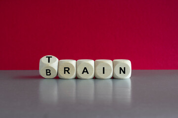 Train your brain. Dice form the words train and brain. Beautiful red background, gray table. Healthcare concept.