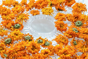 Close-up of vibrant dried orange calendula flowers arranged in a circle on a tray.