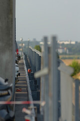 A long row of various cars is parked neatly along the side of a bridge, creating a striking view against the backdrop of the landscape
