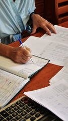Naklejka premium Hands Writing in Ledger Book on Wooden Desk