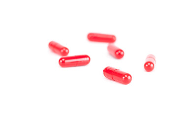 Red medicine capsules scattered on a surface. Concept of painkillers, treatment, overdose, or prescription drugs. isolated on white background with clipping path.