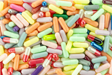 Full frame background of assorted colorful pastel medicine capsules. Pharmaceutical industry pattern, medical texture, or healthcare concept. Top view.