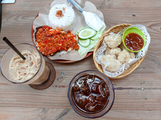 Spicy Indonesian smashed fried chicken (ayam geprek) served with steamed rice, cucumber, lettuce,...