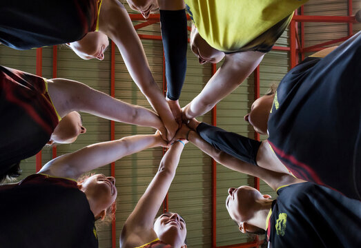Female volleyball team huddling and stacking hands - Powered by Adobe