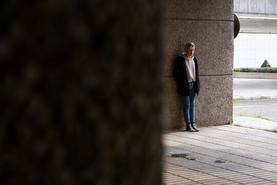 Lonely young man leaning against a wall