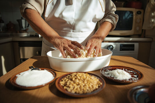 Woman wearing apron kneading dough in bowl at home