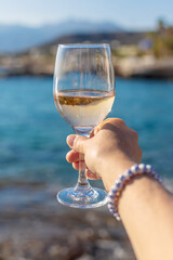 Wine in hands of woman against sea background. Selective focus.
