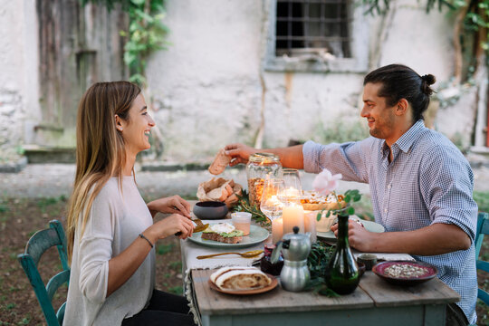 Happy couple having a romantic candlelight meal next to a cottage