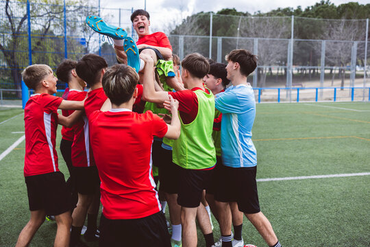Happy soccer team picking up player and celebrating on field