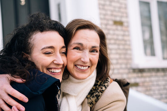 Happy aunt embracing niece outside building