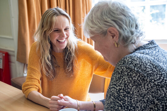 Happy caregiver consoling senior woman at retirement home