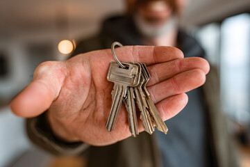 Hand holding keys to a new apartment building.