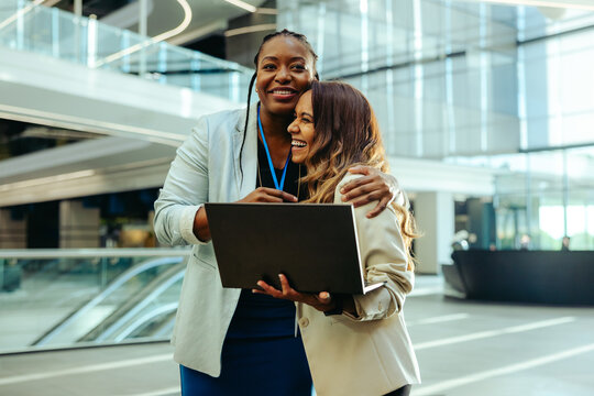 Female colleagues embracing in a modern office lobby