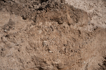 close-up of a textured dirt surface with varying shades of brown showing natural granulation patterns and layers, capturing dry and earthy tones under daylight conditions, outdoors, aggregate, crust