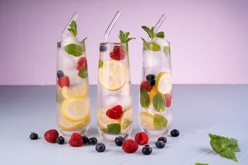 refreshing summer beverages: three tall glasses with lemon, berry, and mint infused sparkling water against a soft gradient background, modern, clear, clean, studio, wet, reflection, smooth, light